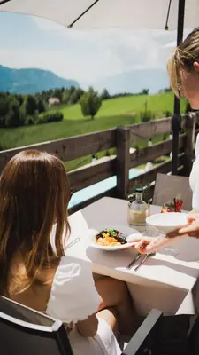two women sitting at a table with a plate of food at Pippos Mountain Lodge in Soprabolzano