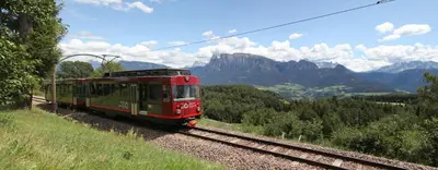 a red train traveling down the tracks in the mountains at Haus Pichler Apartment in Collalbo