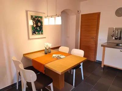 a dining room with a wooden table and white chairs at Haus Pichler Apartment in Collalbo