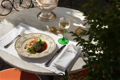 a table with a plate of food and a glass of wine at Weisses Rössl in Caldaro