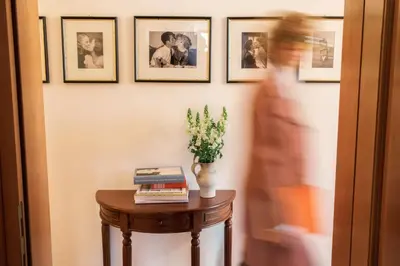 a person walking past a table with a vase of flowers at Weisses Rössl in Caldaro
