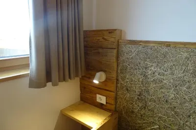 a bedroom with a bed with a desk and a window at Schmalzlhof in Siusi