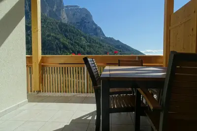 a table and chairs on a balcony with a view of a mountain at Schmalzlhof in Siusi