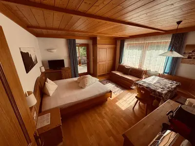 a room with a bed and a couch and a table at Haus Bergfrieden Seiser Alm in Siusi