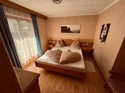 a bedroom with a bed with pillows and a window at Haus Bergfrieden Seiser Alm in Siusi
