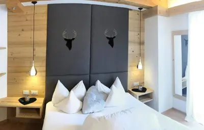 a bedroom with a white bed with a black headboard at Attico Faloria Luxury in Moena