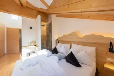 a bedroom with a large white bed with wooden ceilings at Attico Faloria Luxury in Moena