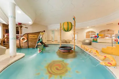 a indoor pool in a hotel room with a water slide at Tyrol family retreat in Naturno