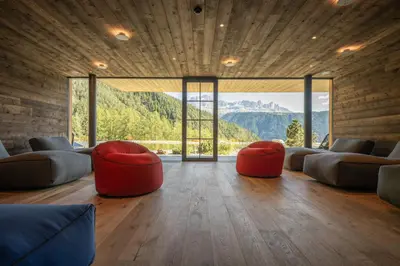 a living room with two red chairs and a large window at Ansitz Velseck-Residence Hotel in Tires