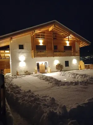 a house in the snow at night at Agriturismo Maso Schneider in Cavalese