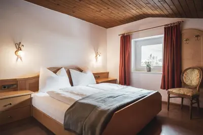 a bedroom with a bed and two lights on the wall at Hotel B&B Frohsinn in Badia