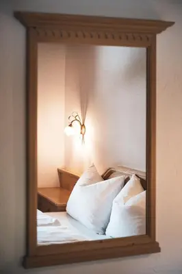 a bedroom with a bed and a window and a chair at Hotel B&B Frohsinn in Badia