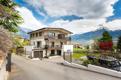 a house with a balcony and mountains in the background at Marlingsuites in Marlengo