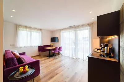 a living room with a purple couch and a kitchen at Marlingsuites in Marlengo
