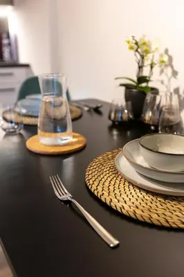 a black table with plates and a fork and a glass at Modern studio apartment in the heart of Merano in Merano