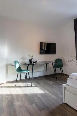 a living room with a desk and a tv on a wall at Modern studio apartment in the heart of Merano in Merano