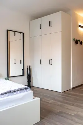 a bedroom with white cabinets and a mirror at Modern studio apartment in the heart of Merano in Merano