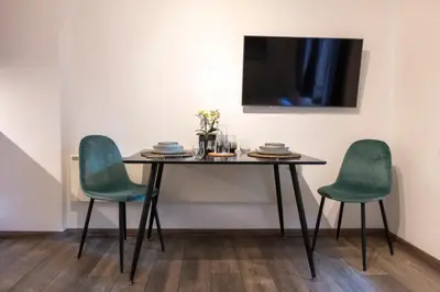 a table with two chairs and a television on a wall at Modern studio apartment in the heart of Merano in Merano