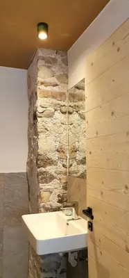 a bathroom with a sink and a stone wall at Ritschhof in Castelrotto