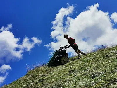 a man walking up a hill with a tractor at Ritschhof in Castelrotto