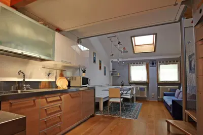 a kitchen and living room with a couch and a table at Wonderful Attic in Dolomite's Heart in Selva di Cadore