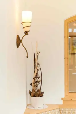 a lamp and a plant in a white bowl on a table at Apartments Sunela in Selva di Val Gardena