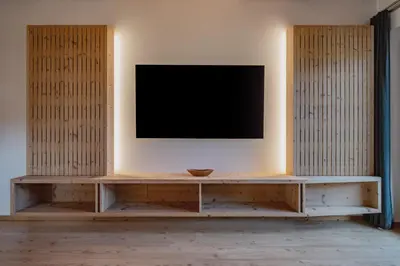 a tv on a wall in a room with a table at Apartments Sunela in Selva di Val Gardena