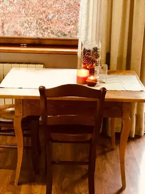 a wooden table with two chairs and a window at Appartamenti Pichler in Castello di Fiemme