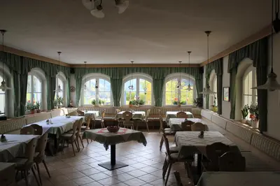 a dining room with tables and chairs and windows at Gasthof Bundschen in Sarntal