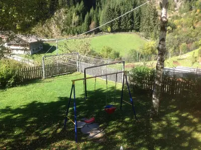 a swing set in a yard next to a tree at Gasthof Bundschen in Sarntal