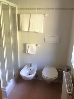 a white bathroom with a toilet and a sink at Gasthof Bundschen in Sarntal