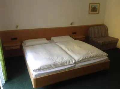 a bedroom with a bed and a chair in it at Gasthof Bundschen in Sarntal