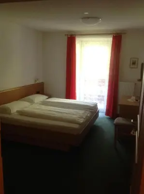 a bedroom with a bed and a window with red curtains at Gasthof Bundschen in Sarntal