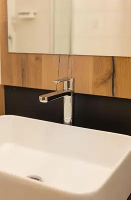 a bathroom sink with a faucet in front of a mirror at Hotel Garni Christin in Ora/Auer