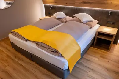 a large bed with a yellow blanket on it at Hotel Garni Christin in Ora/Auer