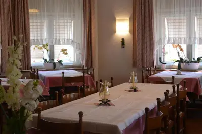 a dining room with two tables and two windows at Hotel Garni Christin in Ora/Auer