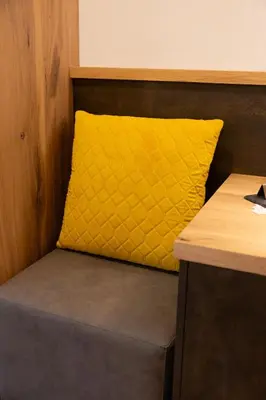 a yellow pillow sitting on top of a bench at Hotel Garni Christin in Ora/Auer