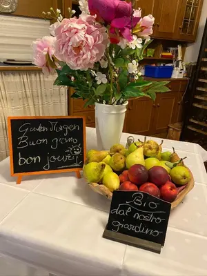 a basket of fruit on a table with a sign and flowers at Villa Vera in Ora/Auer