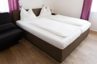 a large bed with white sheets and pillows on it at Gasthaus Abram in Ora/Auer