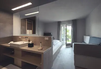 a bathroom with a sink and a bed and a mirror at Das Wanda in Caldaro