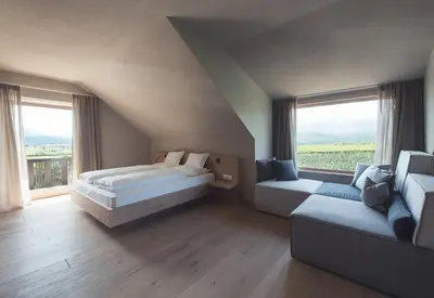 a bedroom with a bed and a couch and windows at Das Wanda in Caldaro
