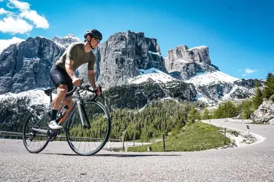 a man riding a bike down a road in the mountains at Hotel Mesdi in Arabba