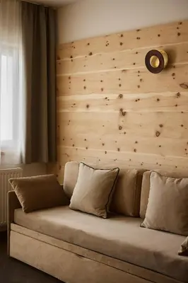 a couch in a room with a wooden wall at Hotel Mesdi in Arabba