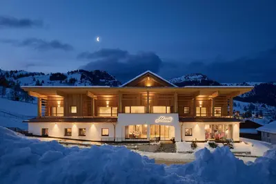 a large house in the snow at night at Hotel Mesdi in Arabba