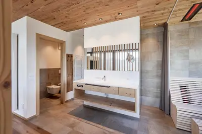 a living room with a gray couch and wooden walls at Hotel Fischer in Bressanone