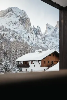 a building covered in snow with mountains in the background at Appartamenti Ciasa Hanny in Colfosco