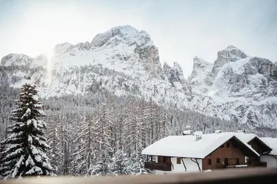 a house with a snow covered mountain in the background at Appartamenti Ciasa Hanny in Colfosco