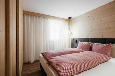 a bedroom with a bed with a wooden wall at Appartamenti Ciasa Hanny in Colfosco