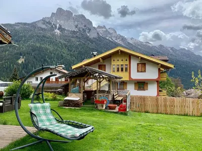 a swing in a yard in front of a house at Casa di Franz in Vigo di Fassa
