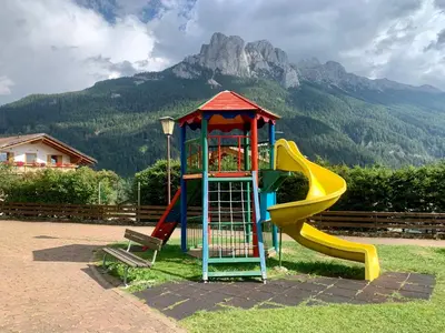 a playground with a slide in front of a mountain at Casa di Franz in Vigo di Fassa